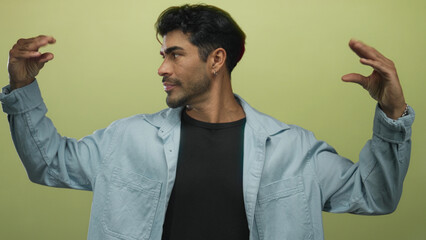 Man gesturing with both hands in a light green studio setting while speaking with hand movements;...