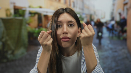 Woman with raised fists and open mouth on a narrow city street with blurred pedestrians behind her;...