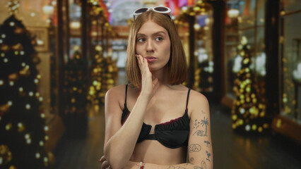 Woman pondering outdoor night urban setting wearing bikini sunglasses tattoos in festive city...