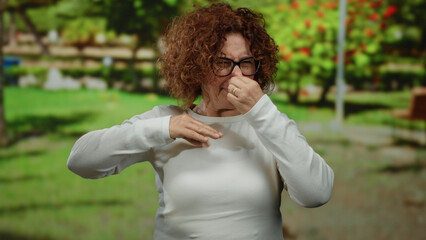Woman in white shirt expressing negative emotion outdoors in park with greenery during daytime...