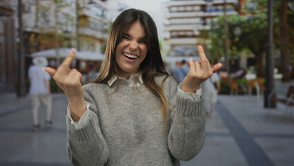 Woman smiling while making a rude gesture outdoors on a city street, capturing urban youth culture...
