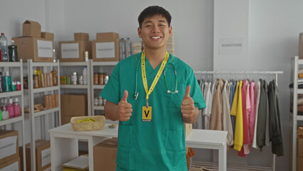 Young man in green scrubs gives thumbs up in a charity donation center room, showcasing teamwork...