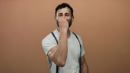 Hispanic man with a beard making a chef's kiss gesture against an orange background, exuding...