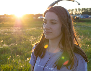 Woman listening to music in a field at sunset