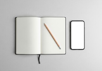 Minimalist workspace with blank notebook and smartphone mockup for creative planning concept