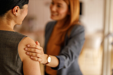 Businesswoman offering comfort and support to her colleague by touching her shoulder during office meeting