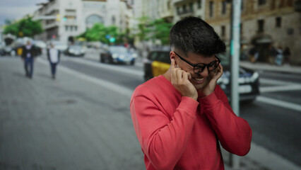 Young man in glasses expressing emotion on a bustling city street background with taxis and pedestrians passing by on a bright day.