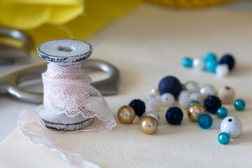 Rustic pink lace spool, blue/gold/white beads, and blurred crafting scissors. Ideal for DIY, handmade crafts, and creative project inspiration.