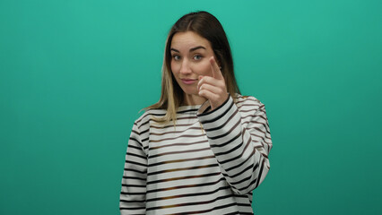 Woman with blonde hair gesturing on an isolated green wall background wearing a striped shirt...