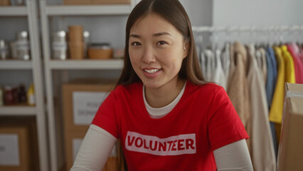Woman volunteer smiling in charity center surrounded by donation goods, highlighting her...