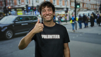 Hispanic man smiling and giving a thumbs-up on a busy street, wearing a volunteer shirt, surrounded...