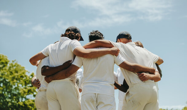 Cricket team huddling together under a bright sunny sky