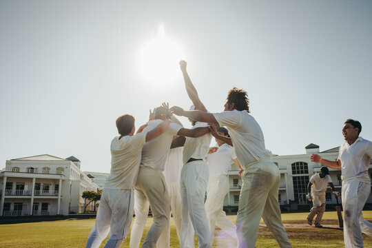 Cricket team celebrating a victorious moment on an outdoor field