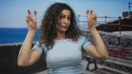 Woman hands making air quotes gesture on a street bench by the seaside promenade; sarcasm irony...