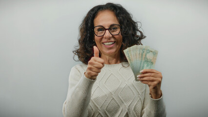 Woman smiling holding uae dirham banknotes making thumbs up on white background suggesting...