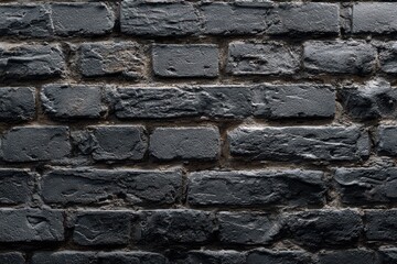 Fototapeta premium Old black shabby brick wall texture displaying uneven surfaces and wear, capturing a sense of history and urban character in a dimly lit environment
