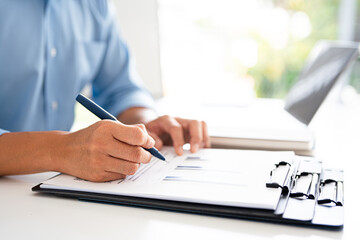 close up hand of Young man in an office setting reviews documents attentively.