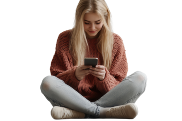 Blonde woman sits on the floor in a cozy sweater while using her smartphone, radiating joy and warmth in an intimate indoor setting