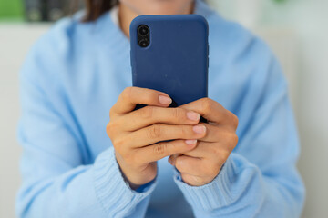 Woman holding blue smartphone, casual clothing, close up, relaxed mood, indoor setting
