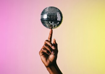 An abstract, playful shot of a hand balancing a small, shiny disco ball on a single finger against a vibrant pink and yellow gradient background.
