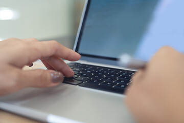 Close up woman typing on laptop computer keyboard with blank screen, working on office table,...