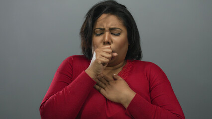 Woman coughing in discomfort against a plain grey background indicating health concerns