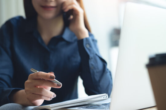 Close up, asian casual business woman talking on mobile phone, discussing with her client during working on laptop computer at coffee shop, freelance at work, business contact