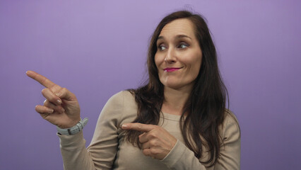 Woman pointing with a confident expression against an isolated purple background, highlighting her expressive gestures and inviting interaction.