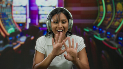 Young woman enjoying music in a casino setting with slot machines in the background, highlighting a relaxed and engaging atmosphere.