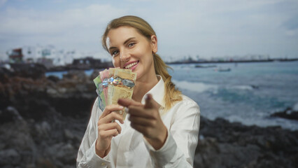 Woman gestures invitingly on a beach holding canadian dollars showcasing a vibrant outdoor setting highlighting financial prosperity and leisure travel.
