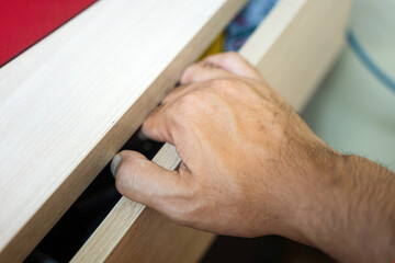 A human hand is pinched by drawer, cause hand and finger injury. Unsafe or hazard at workplace,...