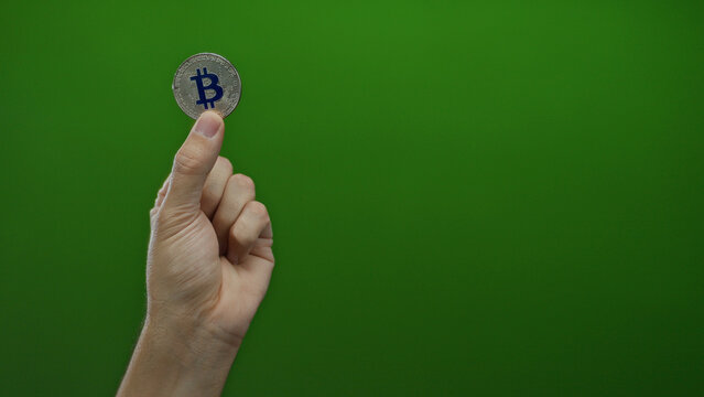 Man holding bitcoin against a green background, showcasing cryptocurrency concept with isolated male hand, symbolizing digital currency economy.