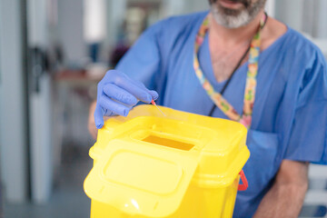 Doctor disposing of needle in sharps container: safe medical waste disposal