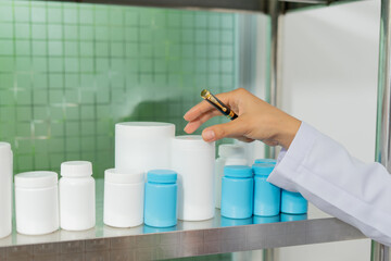 Hand holding pen near white and blue plastic container, laboratory shelf, research concept