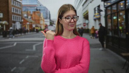 Blonde woman pointing thumb to red brick building in crowded city street during daytime; skepticism...