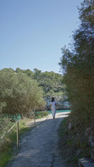 Woman walking in santanyi mallorca along a coastal path surrounded by lush greenery and turquoise...