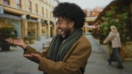 Smiling man presents something in a vibrant outdoor city street, showcasing joy and excitement surrounded by urban architecture and greenery.