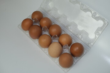 Top view of a dozen brown eggs neatly arranged in a transparent plastic egg carton, placed on a...