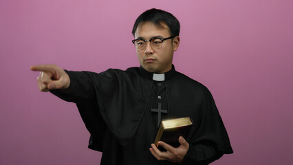 Priest holding bible pointing forward against pink background expressing authority and conviction