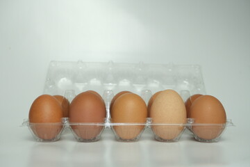 Top view of a dozen brown eggs neatly arranged in a transparent plastic egg carton, placed on a...