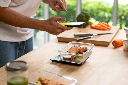 Person using smartphone app for calorie counting and photo sharing above homemade weight loss meal prep.