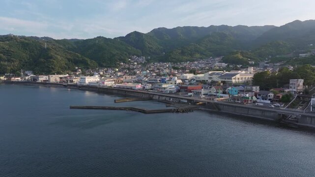 A serene aerial view of Nagahama in Atami, Japan, showing the coastal townscape, harbor, and surrounding mountains at dusk.