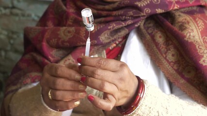 Woman healthcare professional drawing medication into syringe from a vial, National Polio Immunization Drive by the Ministry of Women and Family Welfare, Bihar