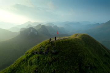 Aerial view of lush green rolling hill with Traditional female farmer with buffalo on Ba Quang Grass Hill surrounded mountain in the morning at Vinh Quy, Ha Lang, Vietnam