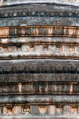 Closeup weathered ancient stupa bese with carved pattern and stains in temple