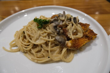 Delicious serving of creamy mushroom pasta paired with a breaded chicken cutlet, garnished with parsley on a white plate.