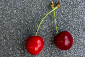 Fresh cherries resting on a gray stone surface with natural lighting in a close-up view