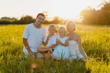 Portrait of happy family: mother, father, children son and daughter on sunset.