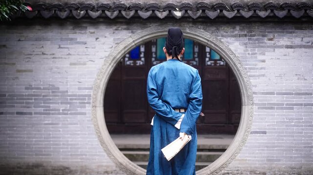 A man in traditional blue robe stands with his back facing the camera at a circular doorway in a classical Chinese courtyard