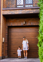 Mother and son standing by garage door. A woman and her young son are standing together in front of...